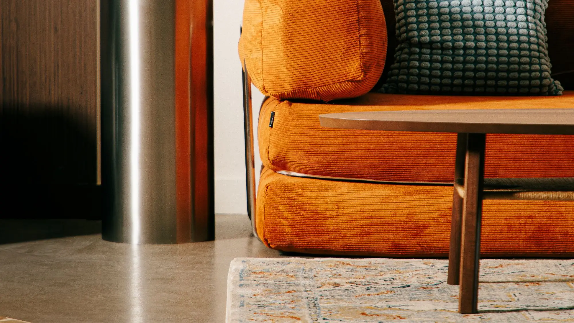 Canape en velours cotele orange, coussin bleu, chez Bernie